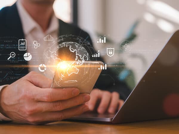 Business Cloud Firewall Features 600x450 Man looking at mobile phone while also on laptop